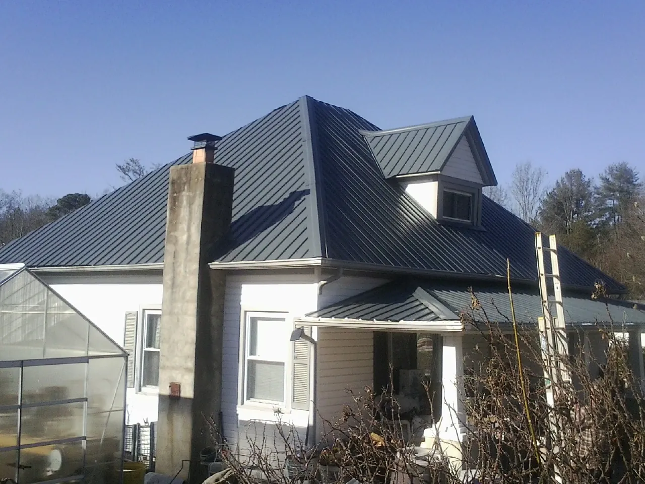 Dark blue standing seam metal roof on a white farmhouse with dormer — Slate & Tile Roof Repair by Roofing Brothers in Pound Ridge