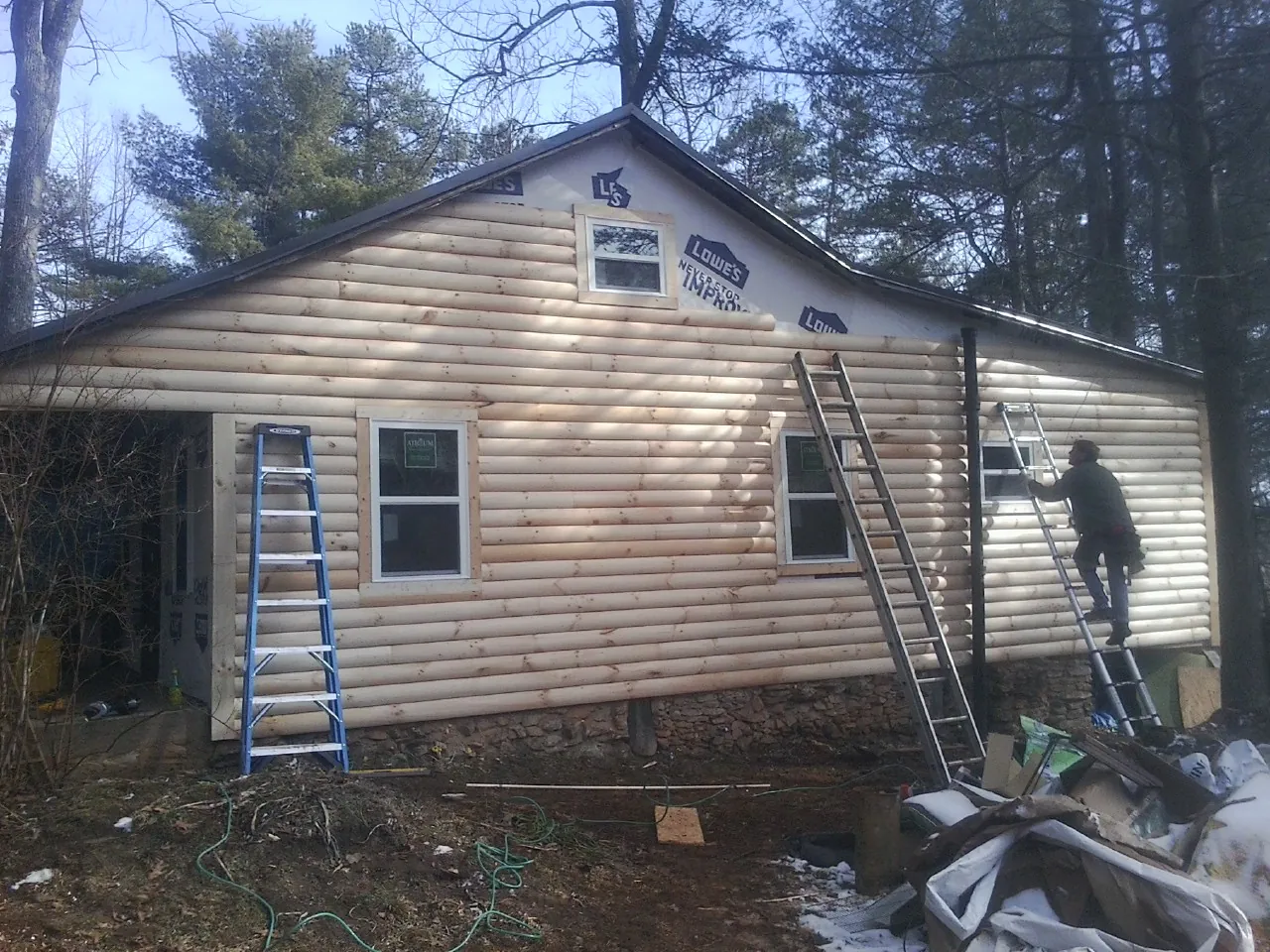 Ladders set against fresh log siding during an exterior remodel in Pound Ridge