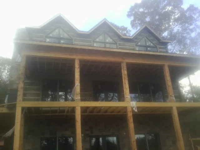 Dormers and porch framing on a large log home under construction — Roof Coating work by our crew in Pound Ridge