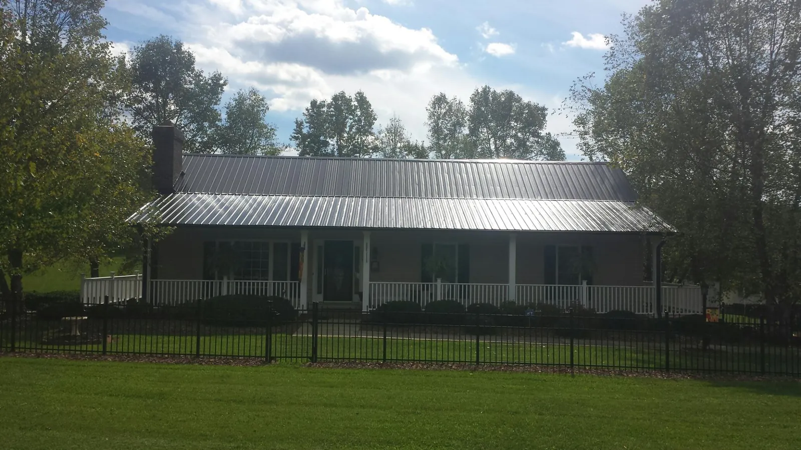 Gray metal roof on a brick ranch with a full width front porch — Gutter Guard Installation work by our crew in Pound Ridge