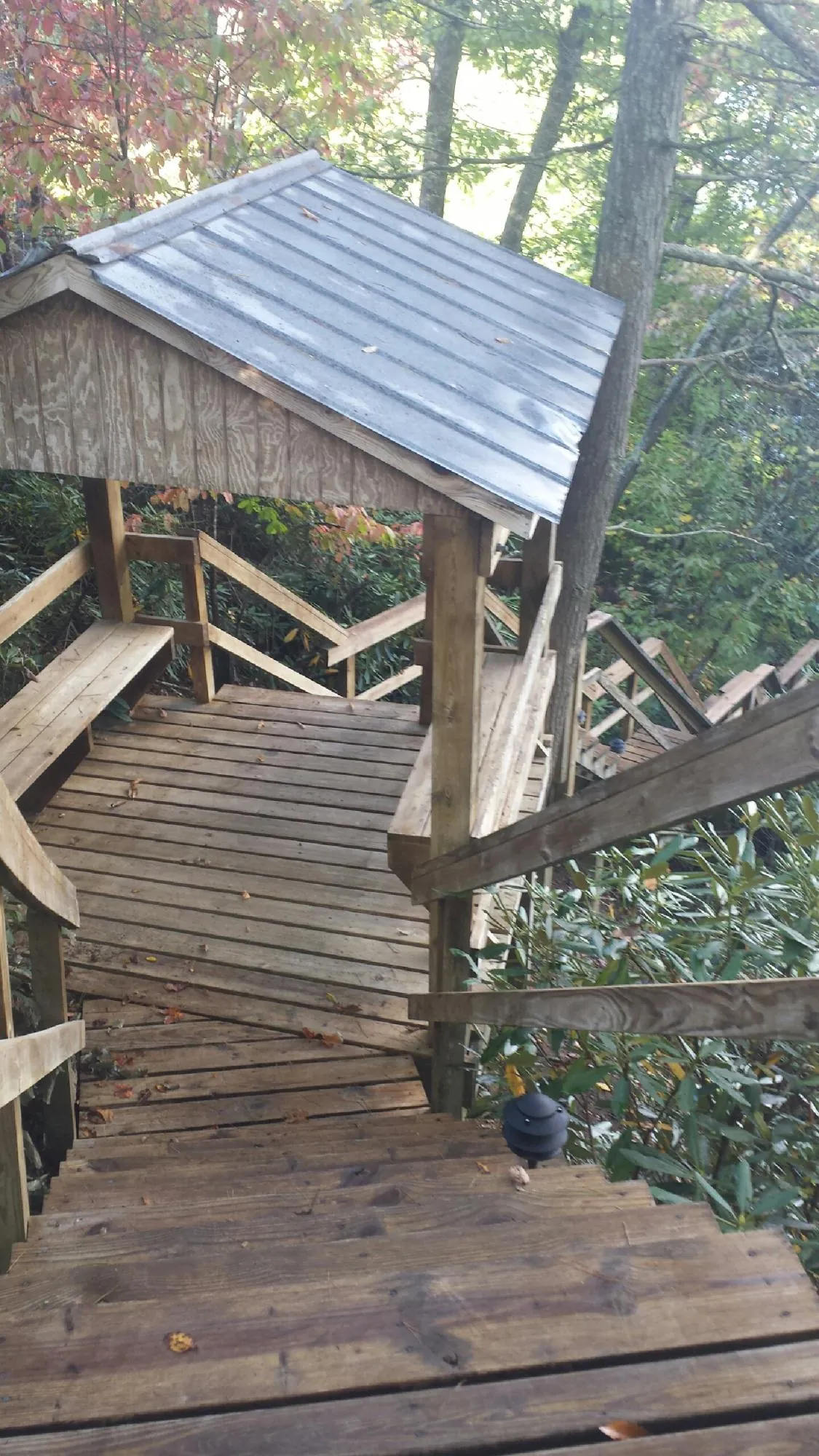 Metal roofed shelter over wooden steps on a wooded walkway — Skylight Repair & Installation work by our crew in Pound Ridge