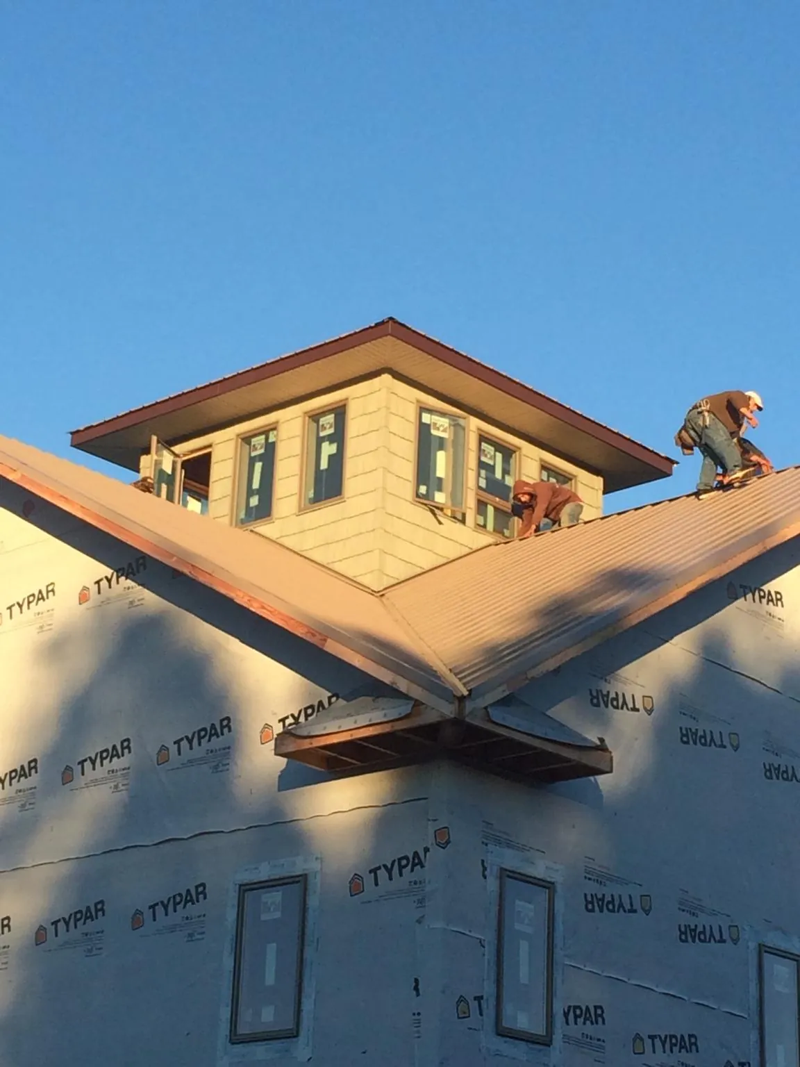 Roofers working around a rooftop cupola on a new metal roof at sunset — Roof Waterproofing in Pound Ridge by Roofing Brothers